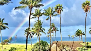 Un paysage tropical avec des palmiers, un bâtiment et une vue sur l’océan.