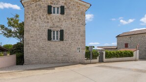 Un bâtiment en pierre avec un toit à deux versants, une petite fenêtre avec des volets et une porte.