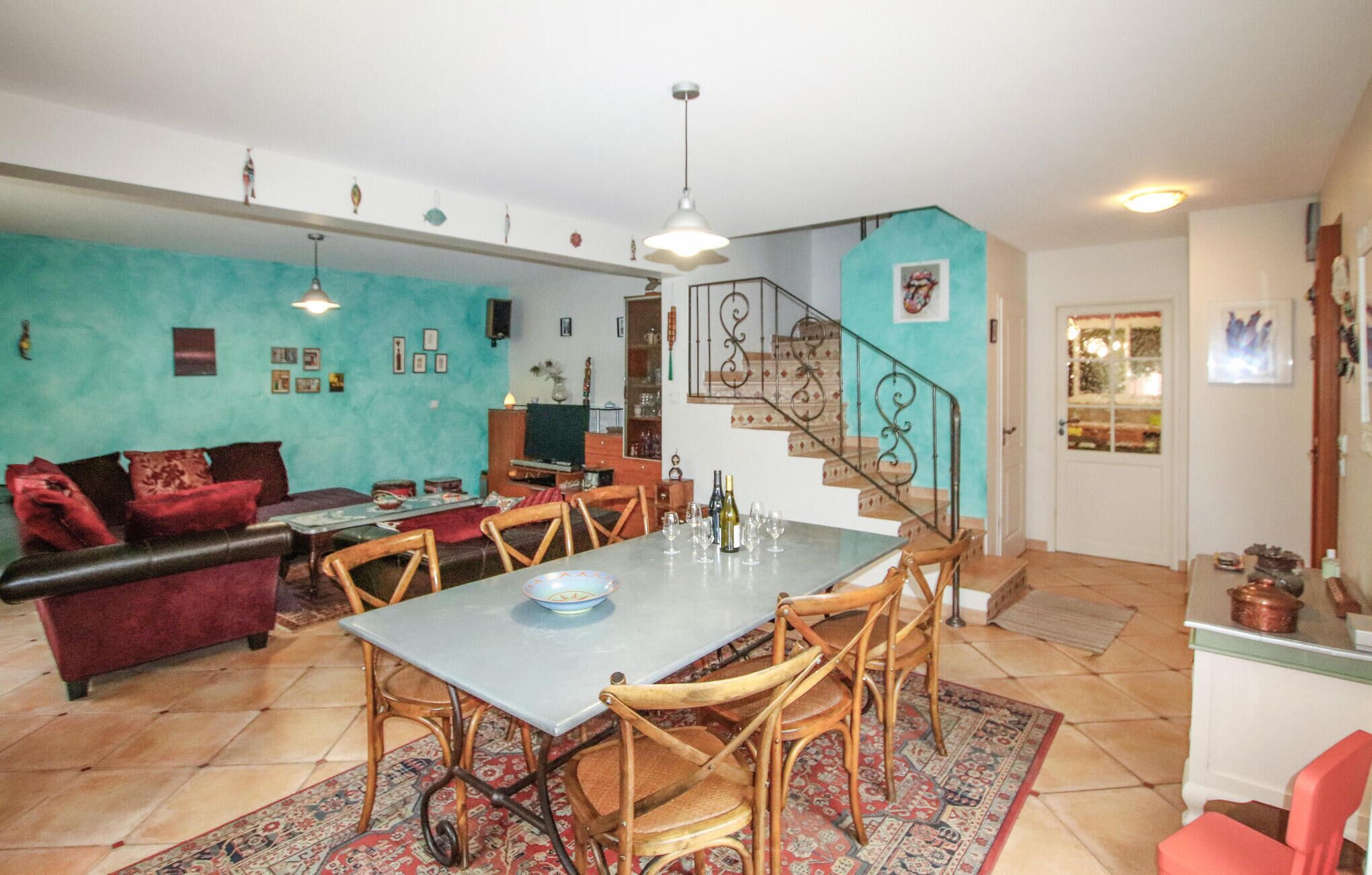 A spacious living area with a dining table, chairs, a sofa, and a staircase.