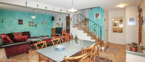 A spacious living area with a dining table, chairs, a sofa, and a staircase.