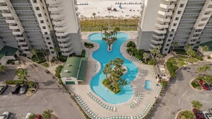 Ein Hochhaus-Hotel mit einem zentral gelegenen Schwimmbecken, umgeben von Liegestühlen und Palmen.