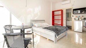 Relax in this serene bedroom with a large bed and adjacent sitting area, featuring a kitchenette with a refrigerator and microwave.
