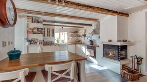 Eine Küche mit weißen Schränken, einem Holztisch und einem Kamin.