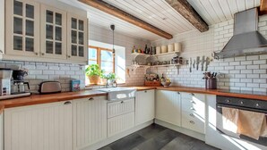 Eine Küche mit weißen Schränken, einer Holz Arbeitsplatte, einem eingebauten Backofen und einem Fenster mit Pflanzen.
