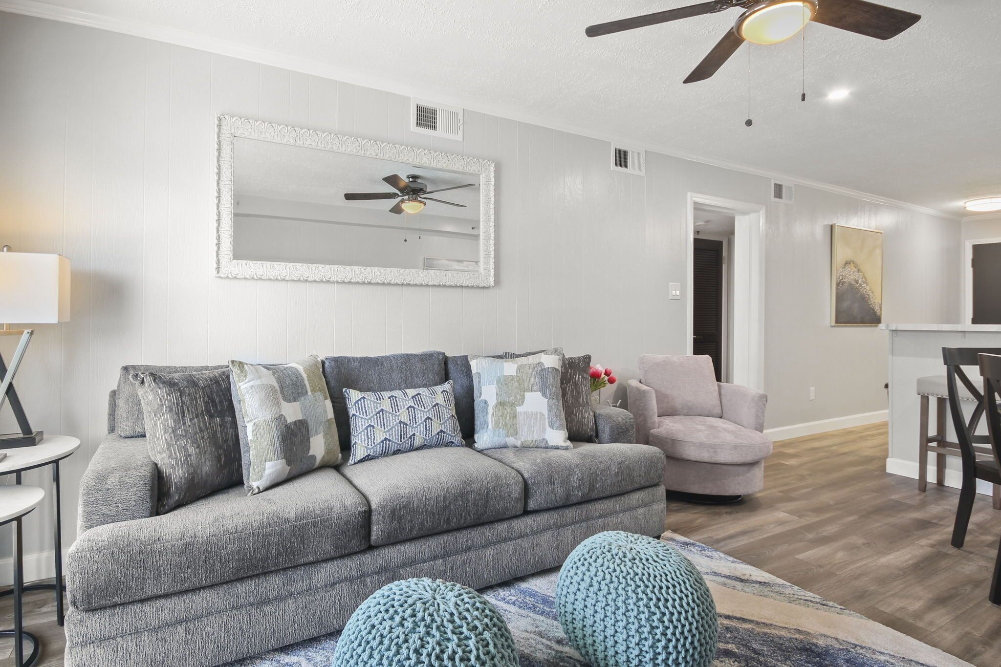 Ein Wohnzimmer mit grauem Sofa, einem runden Couchtisch und einem Deckenventilator.
