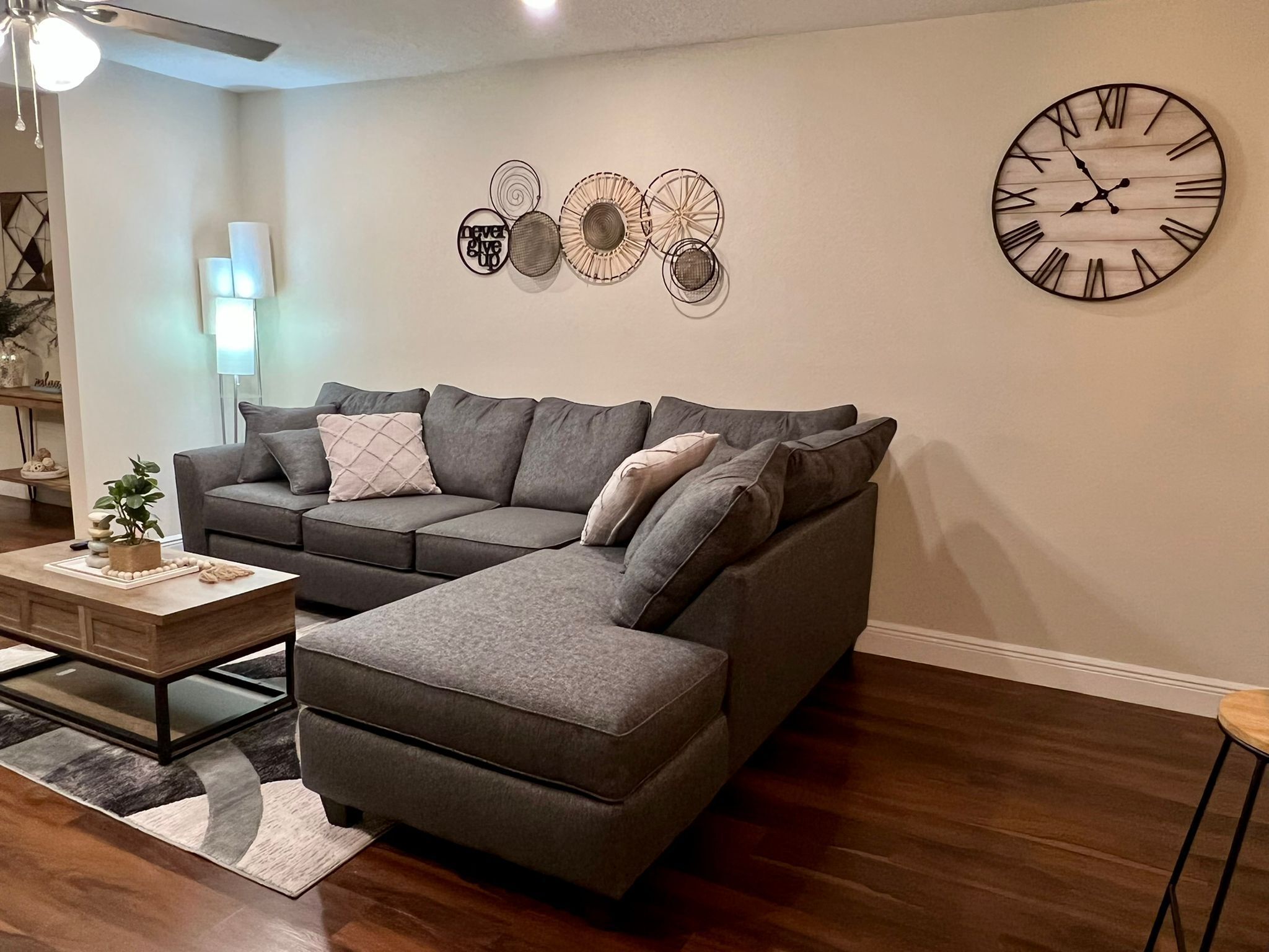 Een moderne woonkamer met een modulaire bank, een bijzettafeltje en decoratieve muurkunst.