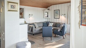 Ett mysigt vardagsrum med en grå soffa, blå fåtöljer och ett litet runt bord.