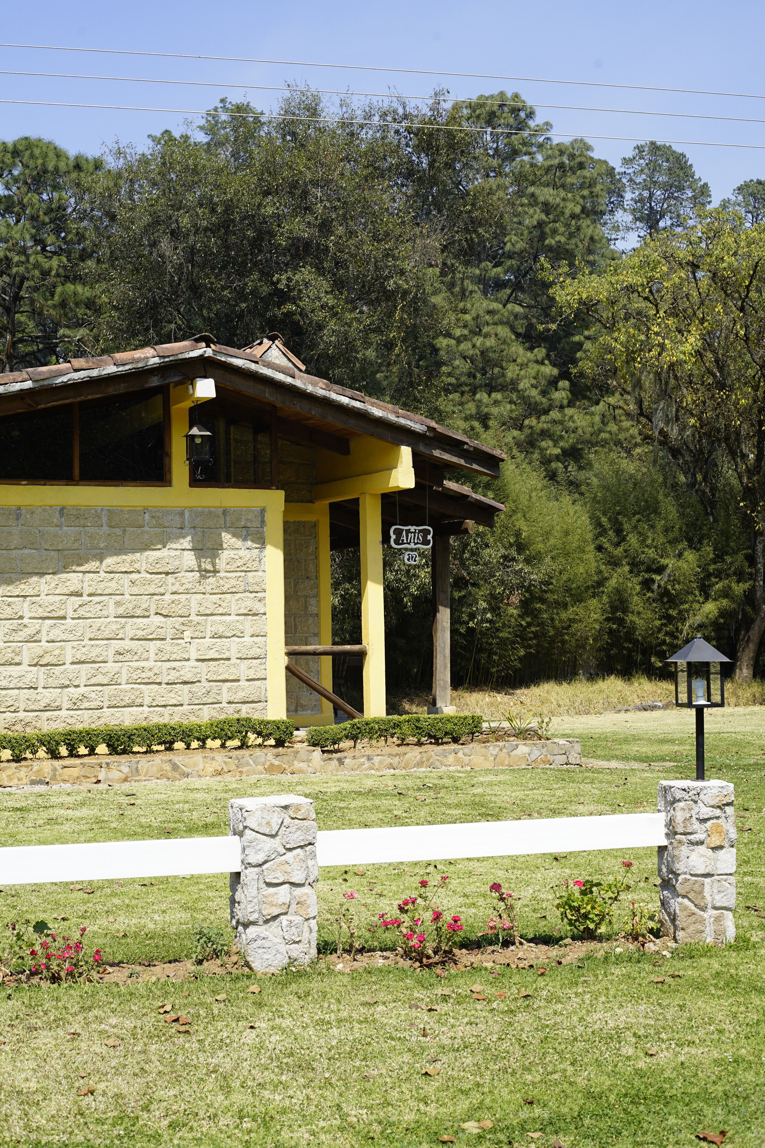 Un bâtiment en pierre avec une façade jaune, un porche et une enseigne sur laquelle on peut lire « Anis ».