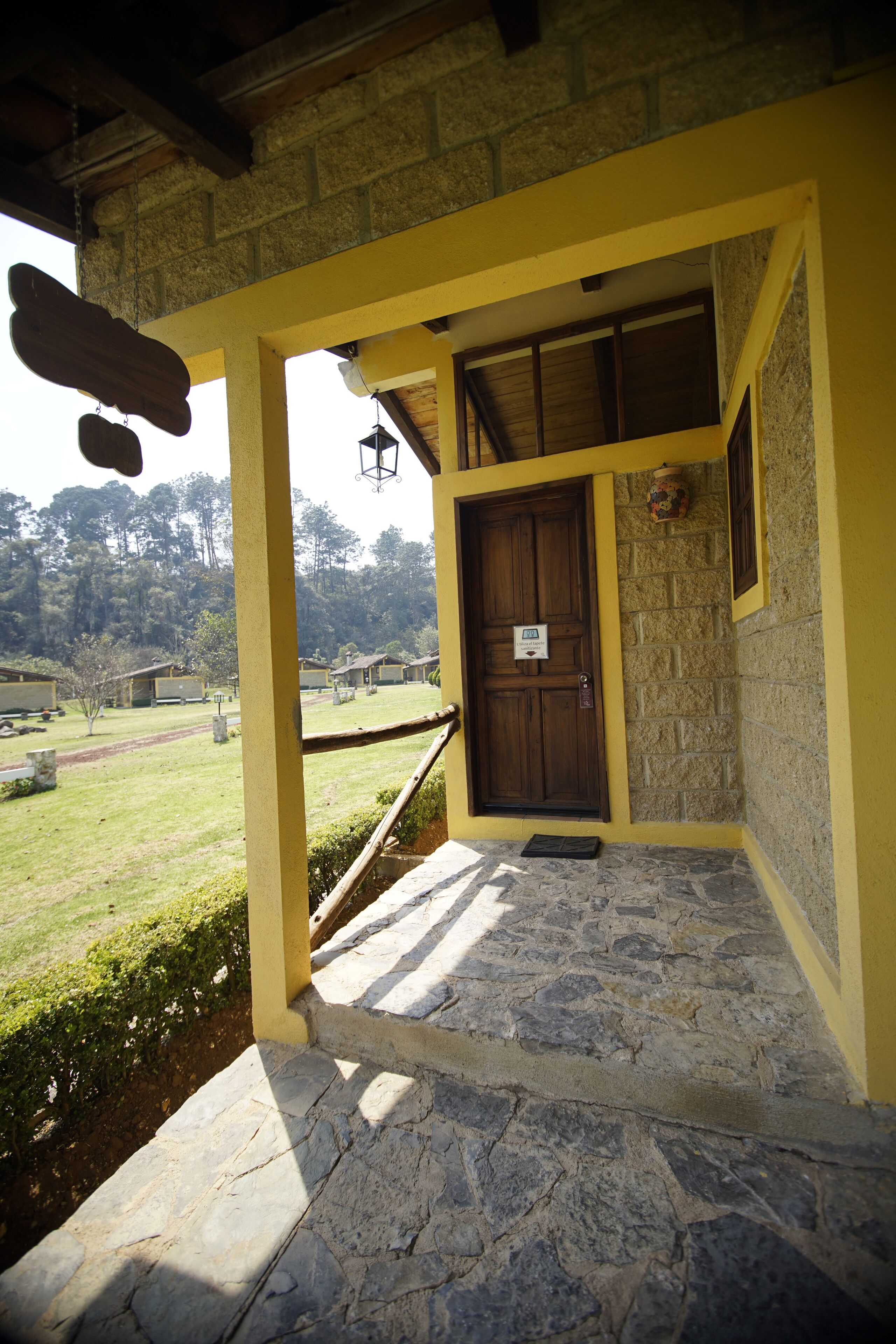 A stone-paved entrance with a wooden door and yellow walls.