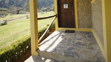 A stone-paved entrance with a wooden door and yellow walls.