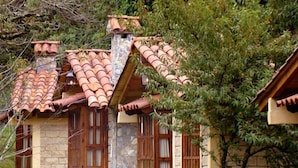 Una casa de piedra con techo de tejas y contraventanas de madera.