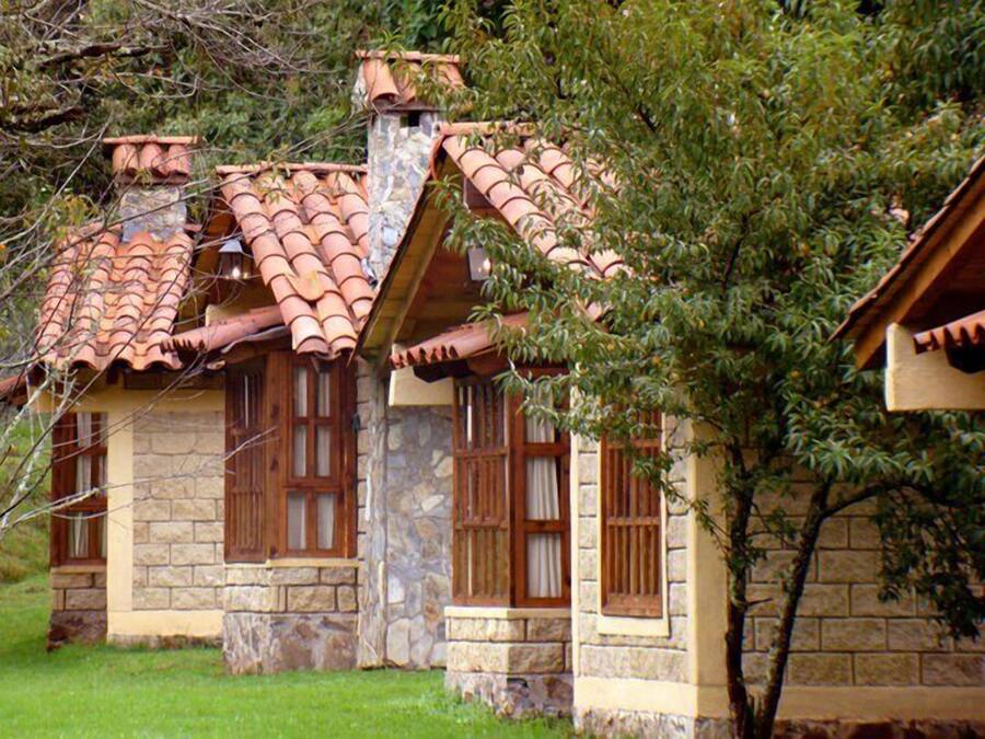 Uma casa de pedra com telhado de telhas e persianas de madeira.