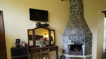 A bedroom with a stone fireplace, a desk with a mirror, and a bed with a red blanket.