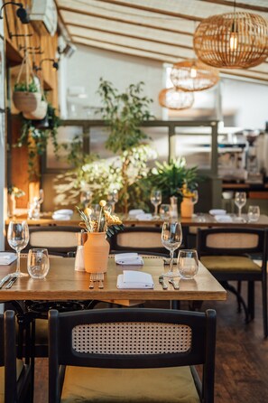 A restaurant interior with wooden tables, wicker chairs, and hanging light fixtures. - The Fox at Willian  (Letchworth)