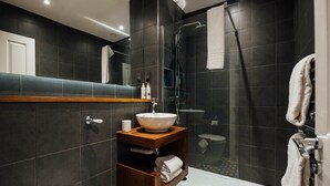 A modern bathroom with a glass-enclosed shower, a white sink with a vessel basin, and a wooden vanity with a towel rack. - The Fox at Willian  (Letchworth)