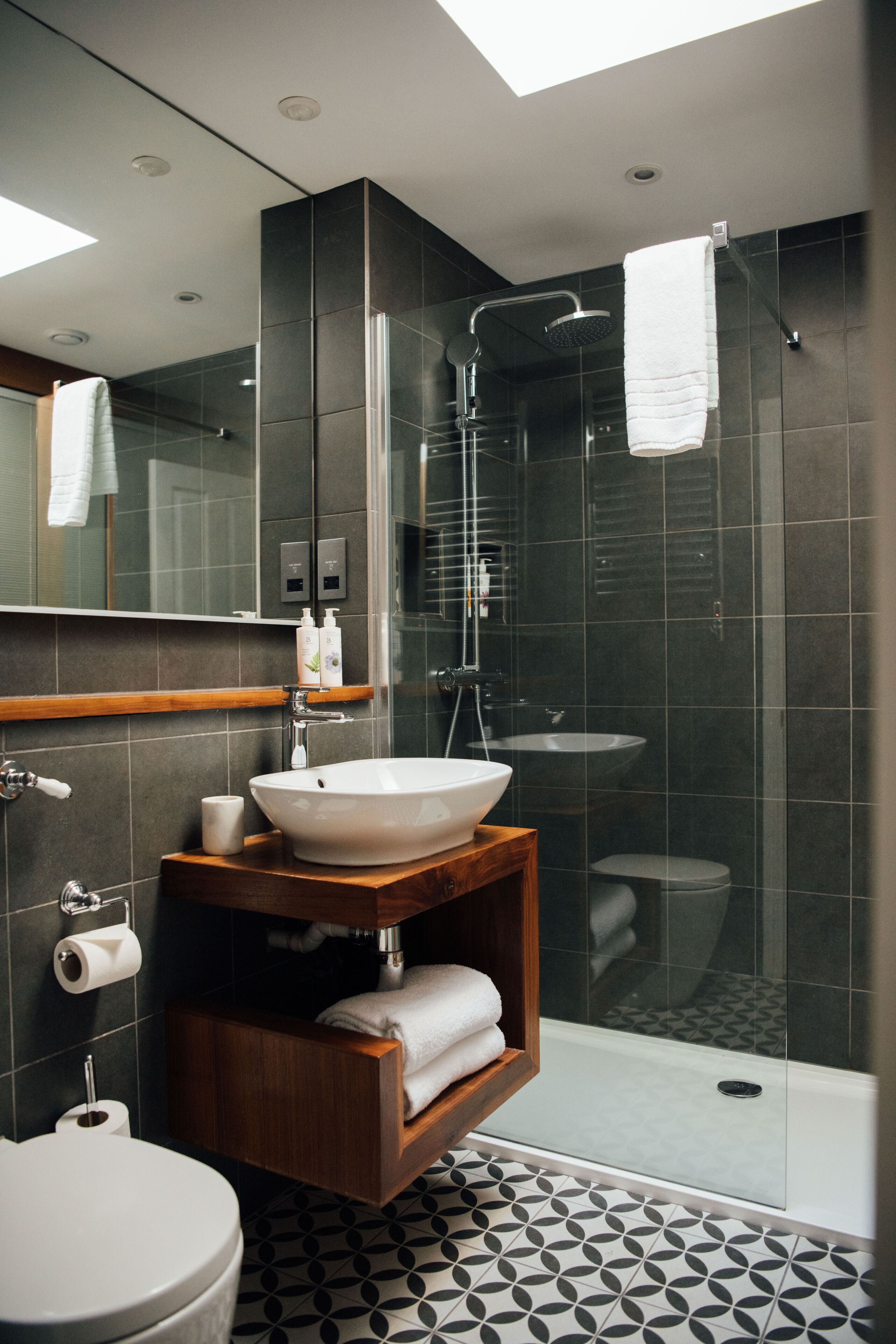 Ein modernes Badezimmer mit Oberlicht, einer freistehenden Badewanne, einem Waschtisch und einer Toilette.