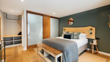 Un dormitorio con una cama, un banco, un taburete pequeño y un espejo en la pared.