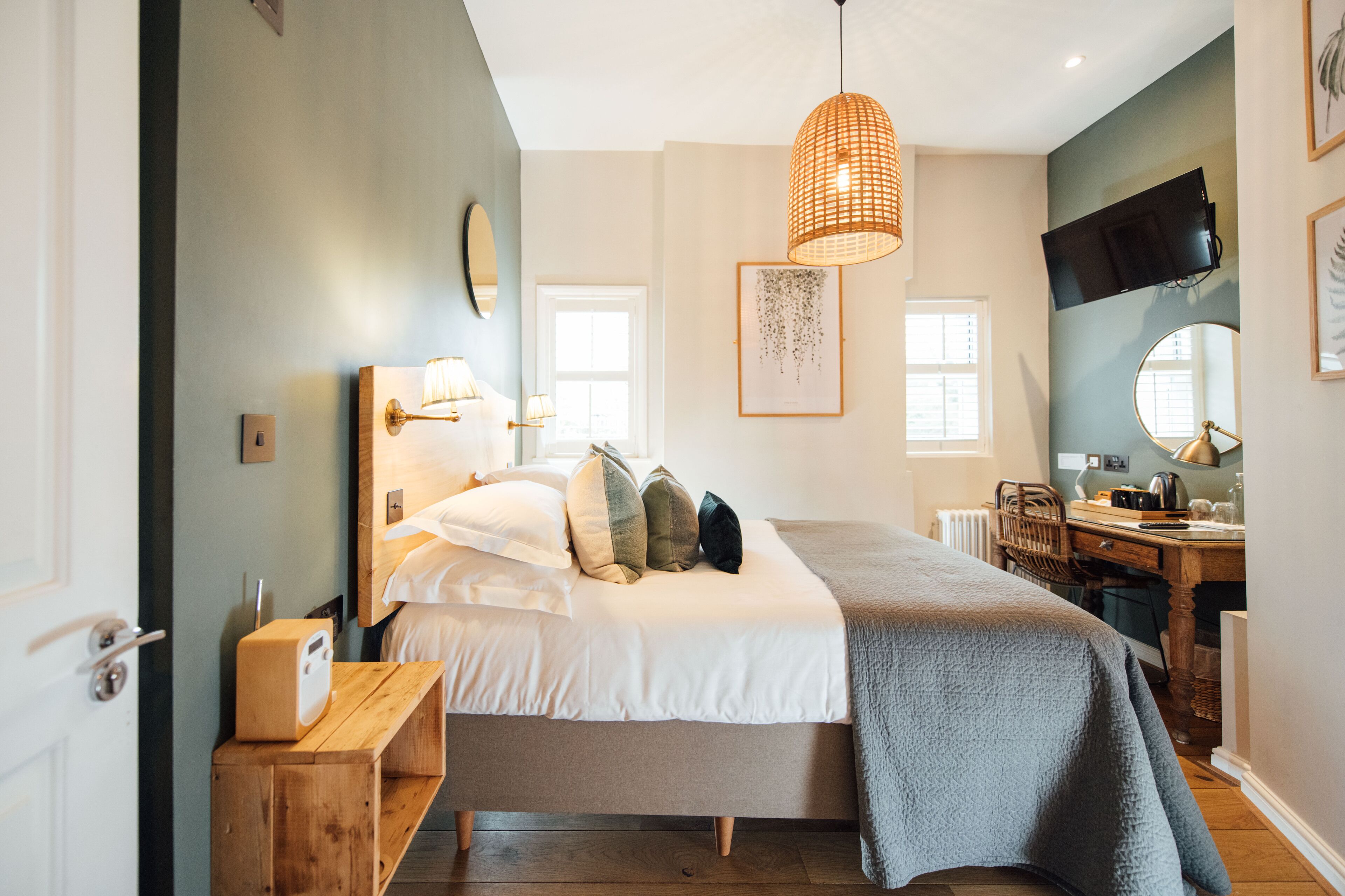 A bedroom with a bed, bedside table, lamp, and a TV mounted on the wall.