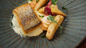 Un plato de comida con un trozo de pescado y verduras sobre un plato con textura.
