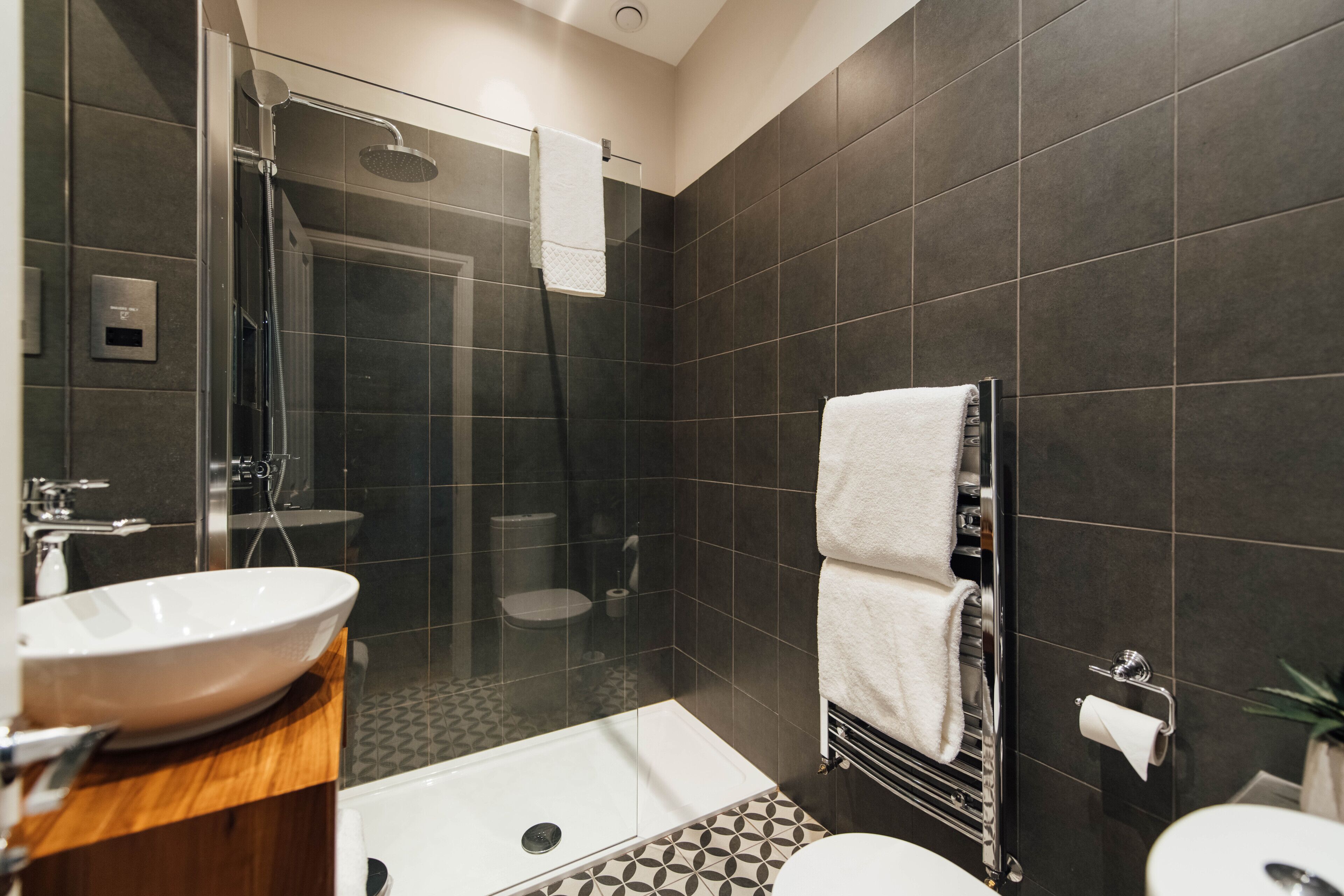 A modern bathroom with a glass-enclosed shower, a bathtub, a sink, and a toilet.