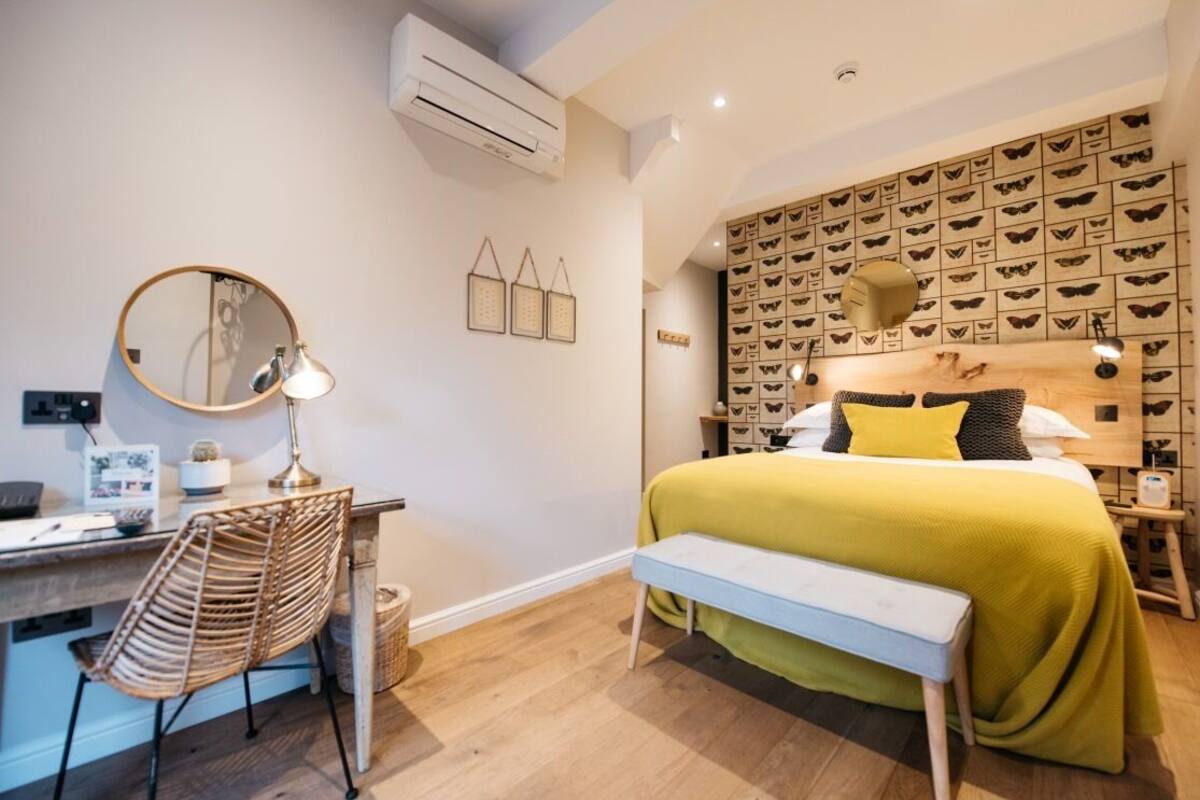 A bedroom with a bed, a desk, a chair, a mirror, and a wall with butterfly decorations.