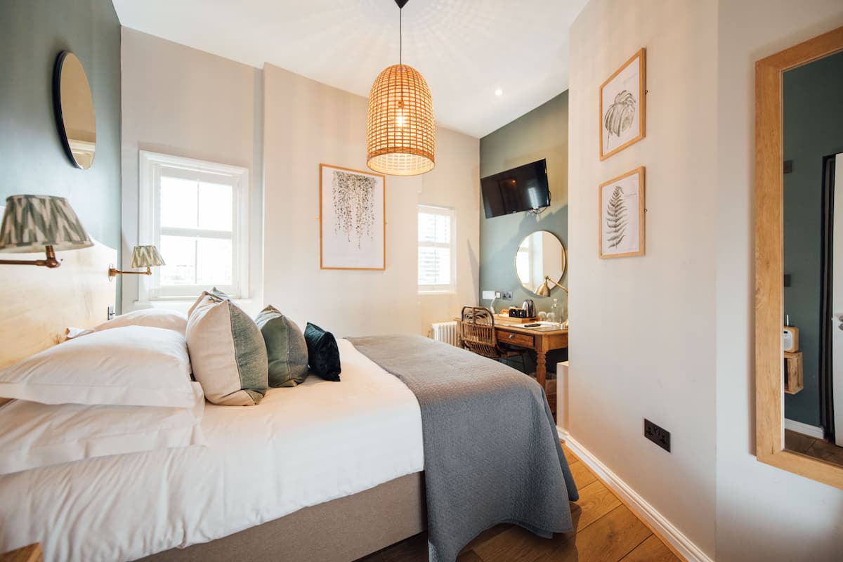 A bedroom with a bed, bedside lamps, a desk, and a chair.