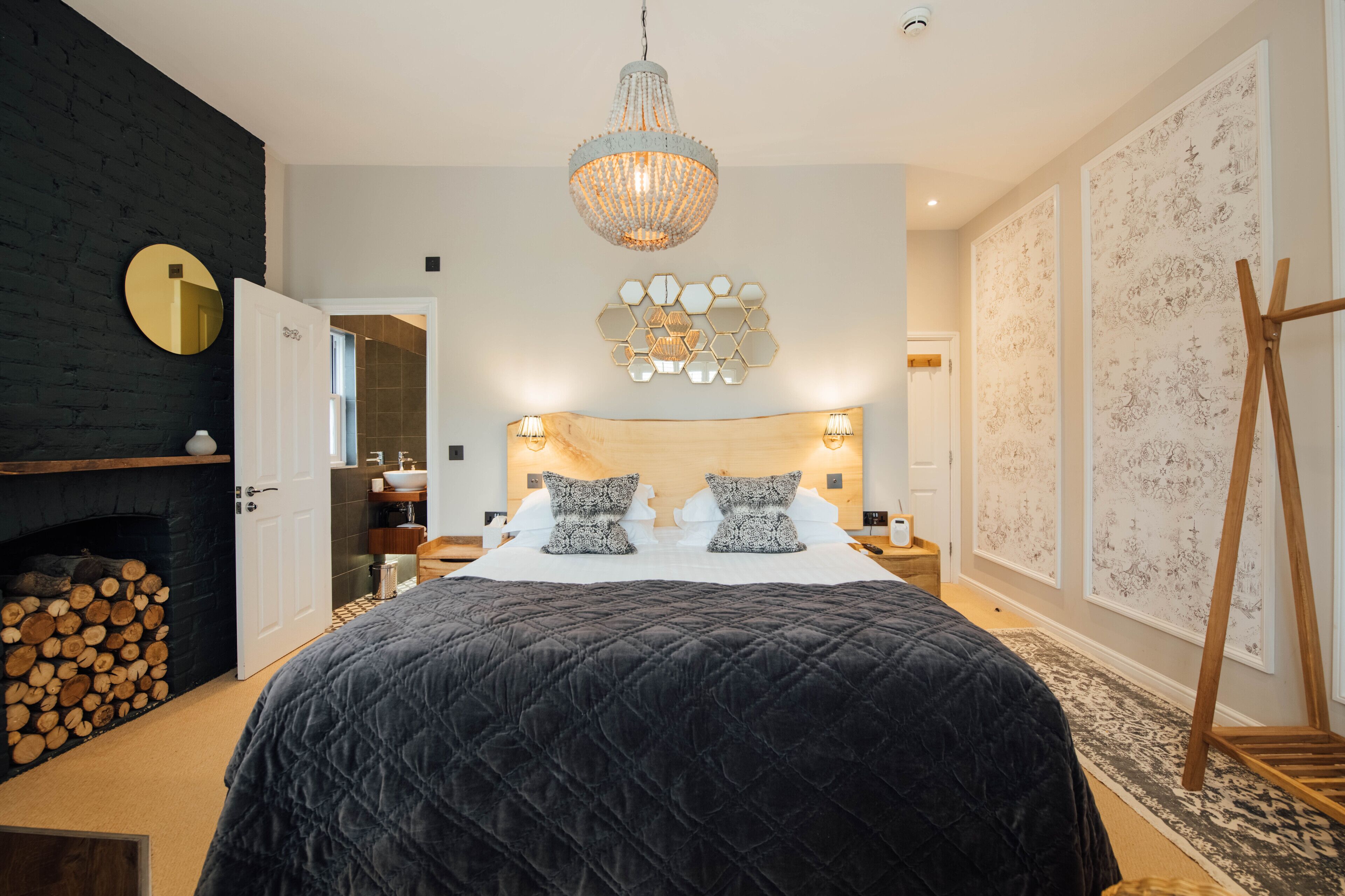A bedroom with a large bed, a chandelier, a wooden headboard, and a fireplace.