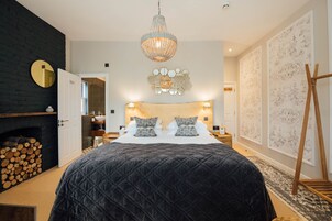 A bedroom with a large bed, a chandelier, a wooden headboard, and a fireplace.