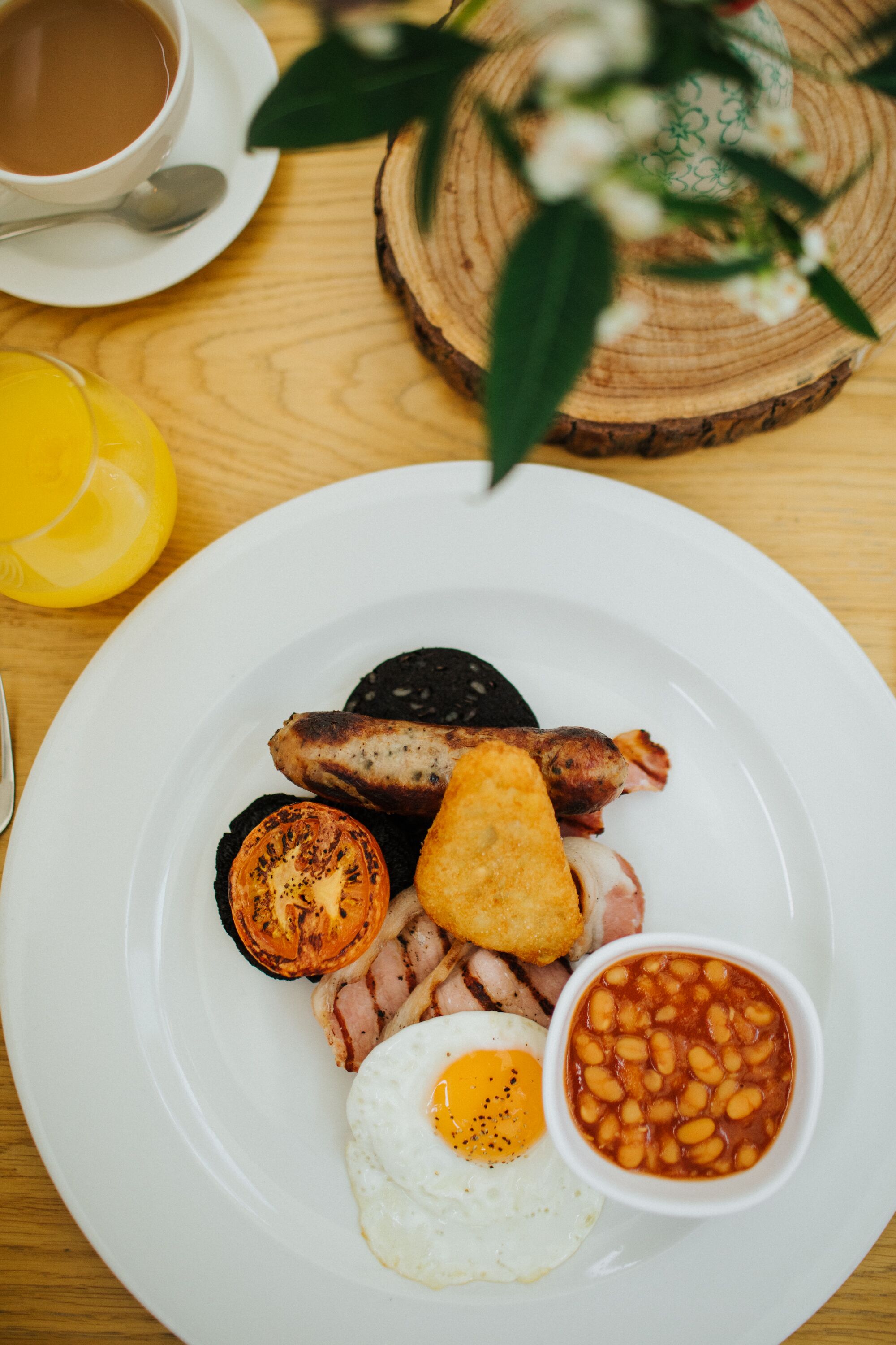 Un plato de comida para el desayuno que incluye huevos, tocino, salchichas y frijoles.