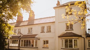 A row of white buildings with multiple windows and a street in front. - The Fox at Willian  (Letchworth)
