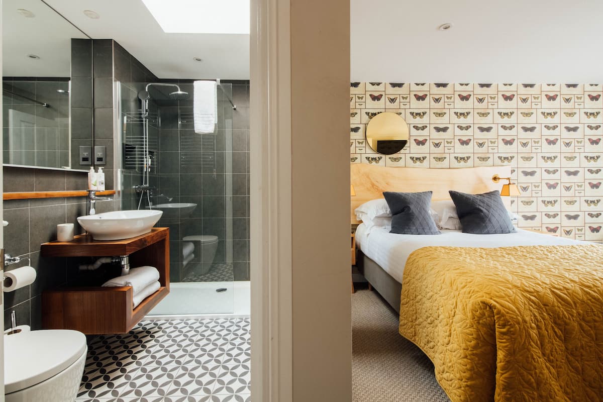 A modern bathroom with a glass shower enclosure, a wooden vanity, and a patterned floor.