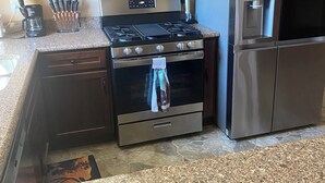 A kitchen with wooden cabinets, a stainless steel stove, a microwave, a refrigerator, and a coffee maker. - Country Home with Pond and Great Outdoor Space (Nashport)