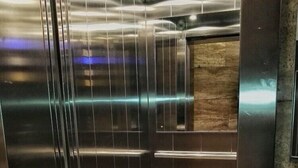 An elevator interior with metallic walls and a wooden panel on the right. - Central City Inn (Bologna)