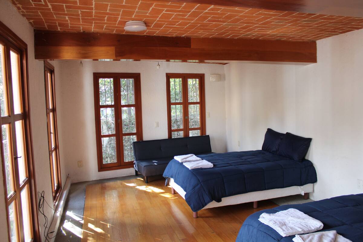 A room with two beds, large windows, and a brick ceiling.