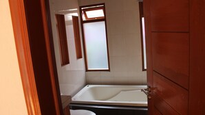 Ein Badezimmer mit Badewanne, Toilette und einem Fenster.