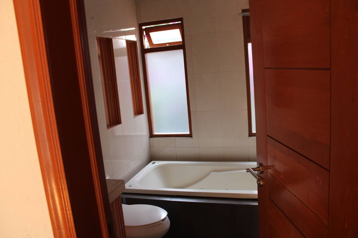 A bathroom with a bathtub, toilet, and a window.