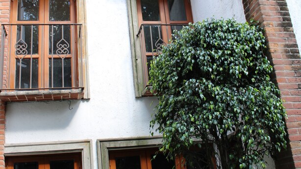 Ein mehrstöckiges Gebäude mit Back- und weißen Wänden, Holzfensterrahmen und einem Balkon mit Metallgeländern.