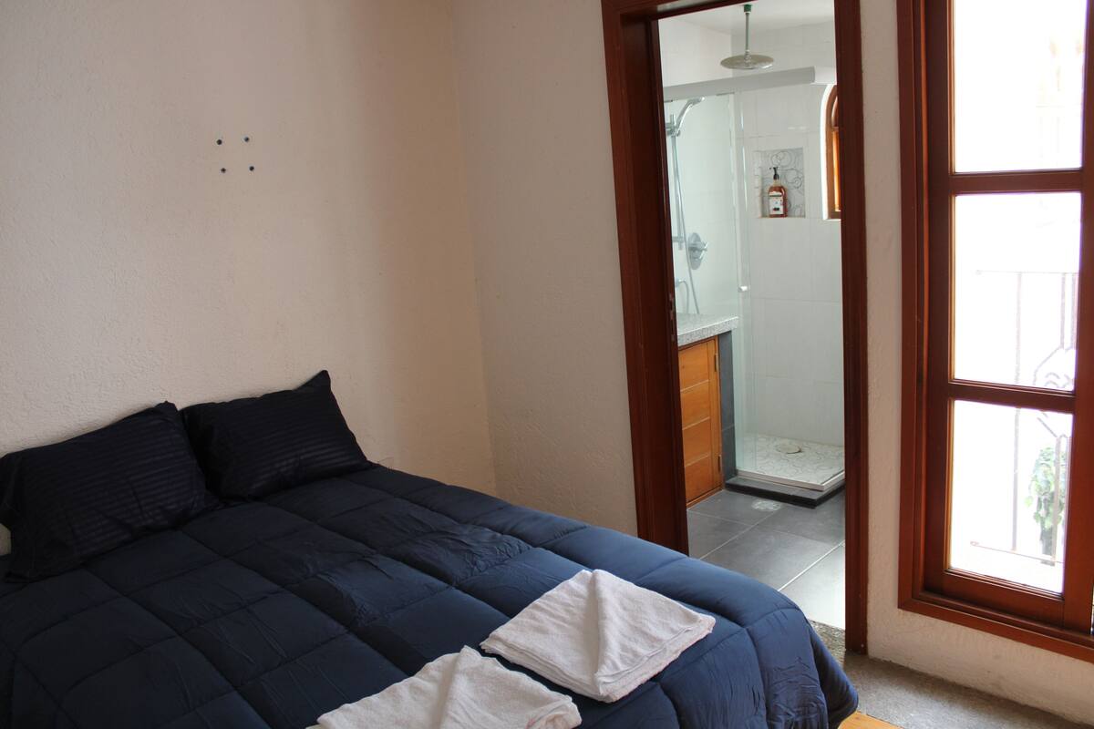 A bedroom with a bed, a window, and a view of a bathroom.