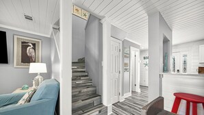 Portaat, joiden askelmat on viimeistelty puulla, turkoosinkankaisella verhoilulla päällystetty tuoli, punainen jakkara ja seinään kiinnitetty lamppu.