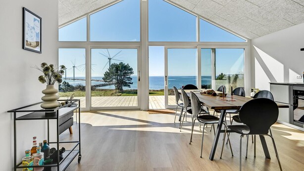 A spacious dining area with large windows offering ocean views, a modern kitchen, and a minimalist decor. - Cozy home in Ebeltoft (Ebeltoft)
