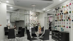 A modern dining area with a glass table, black chairs, and a decorative wall with hanging items. - Samay Business Hotel  (Cusco)