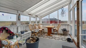 A covered patio with wicker furniture, a table, and a view of the countryside.
