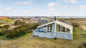 A coastal house with a large window and a small attached shed.