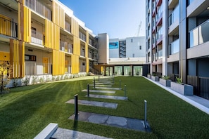 A modern building with a courtyard, balconies, and a sign indicating availability. - City Escape 1-Bedroom Studio with Pool in CBD (Auckland)