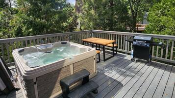 Ein Whirlpool auf einer Holzterrasse mit einem Holztisch und einer Bank.