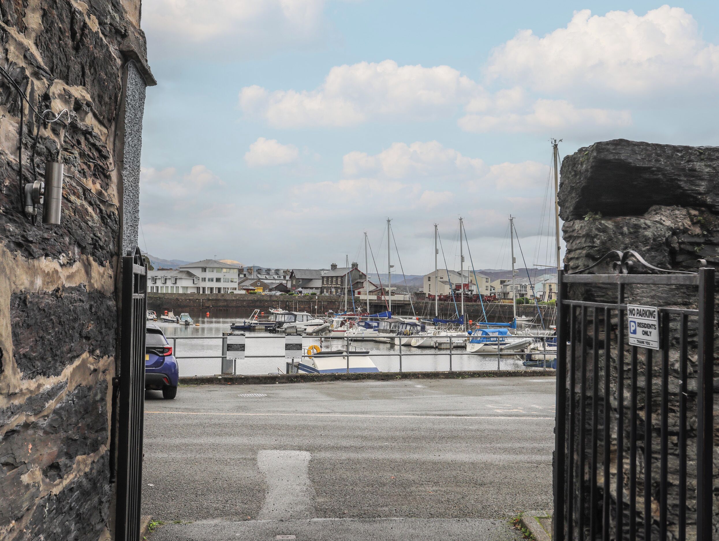 A marina with boats docked, a stone building on the left, and a 'No Parking' sign on the right.