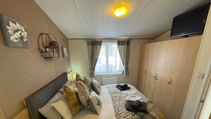 A neatly arranged bedroom with a bed, a nightstand, a TV, and a wardrobe.