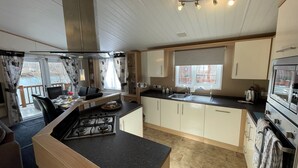 A compact kitchen with a gas stove, a sink, and a built-in oven. There is a dining area with a table and chairs, and a window providing natural light.