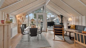 Ett mysigt och väl upplyst vindsrum med en matplats, en sittgrupp med en soffa och ett stort fönster med utsikt över omgivningarna.