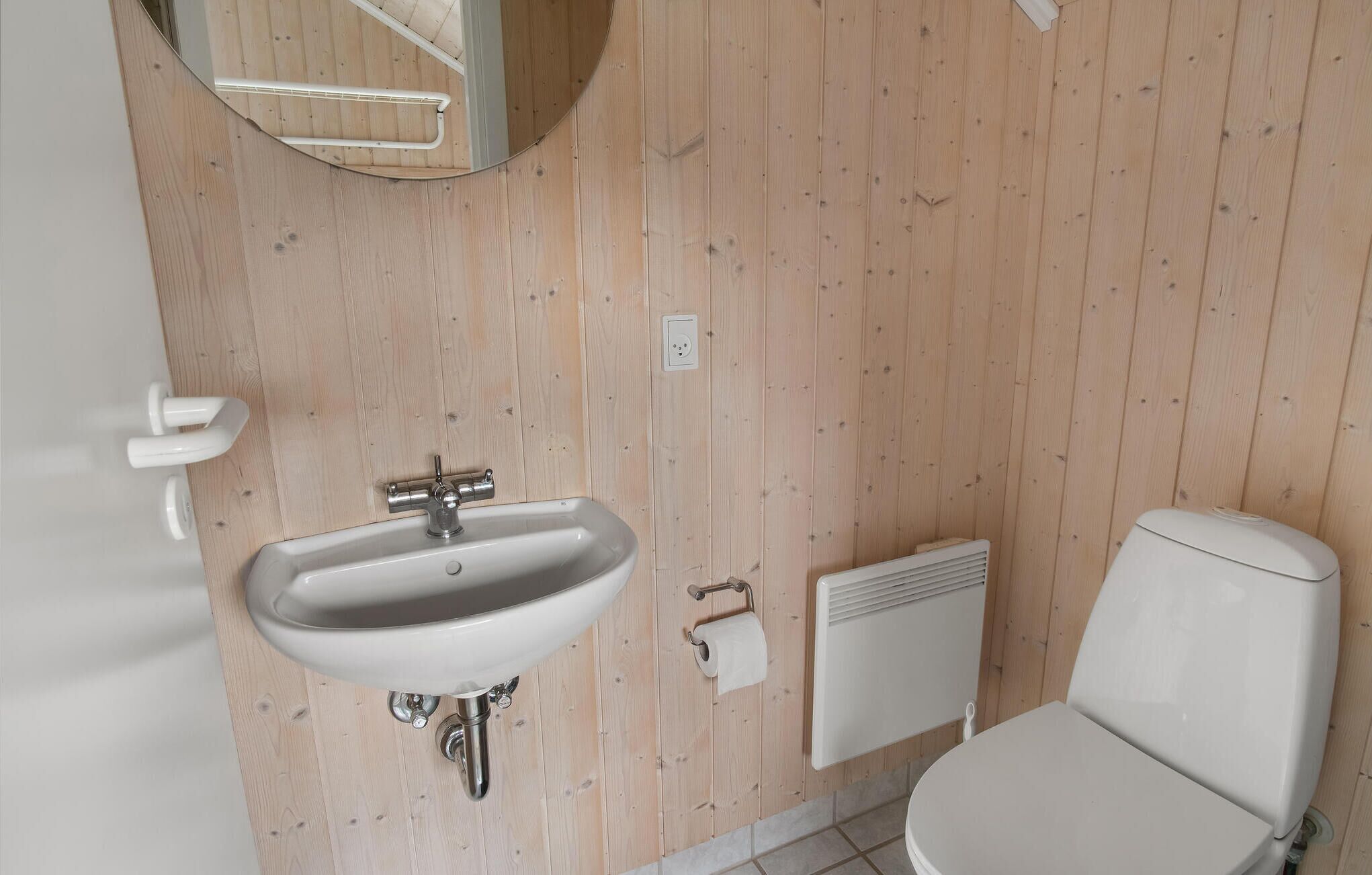 A bathroom with a white sink, toilet, and radiator.